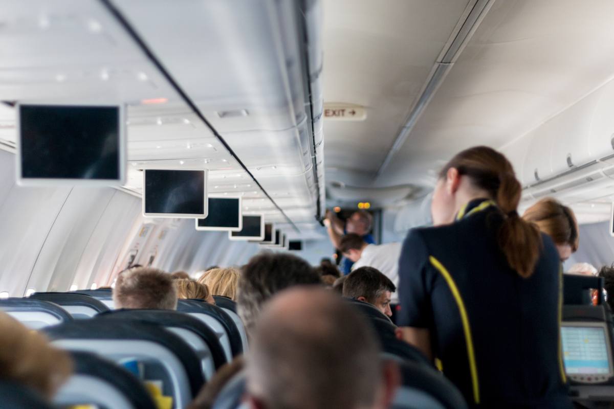 Assistente di volo e passeggeri seduti durante un volo